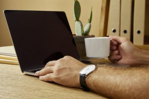 Man working on his business from a laptop while having a cup of coffee