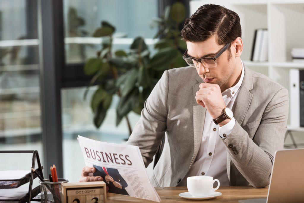 man studying his competition in the business page